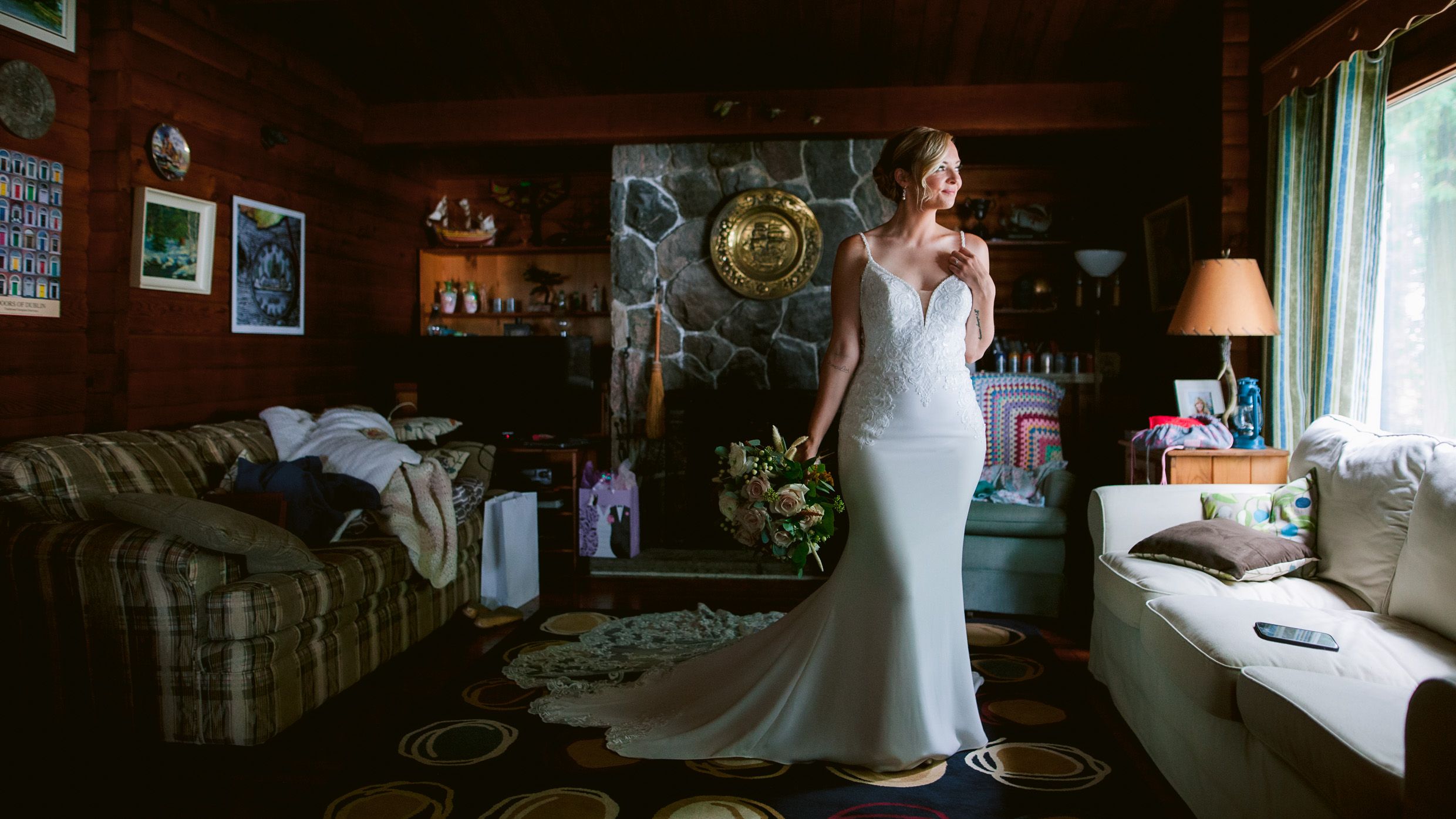 Elegant wedding dress shown in a cozy rustic cabin setting.