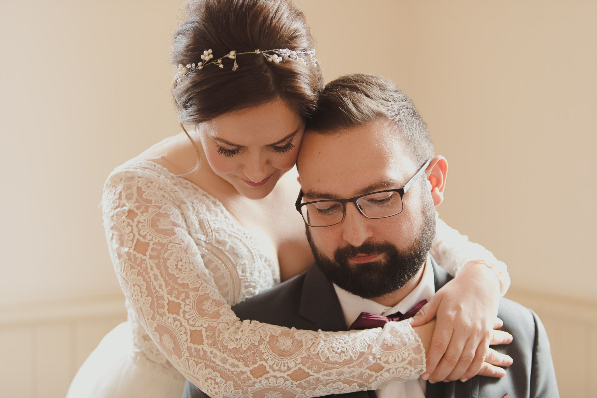 Intimate wedding portrait in soft lighting showing tender embrace and lace details.