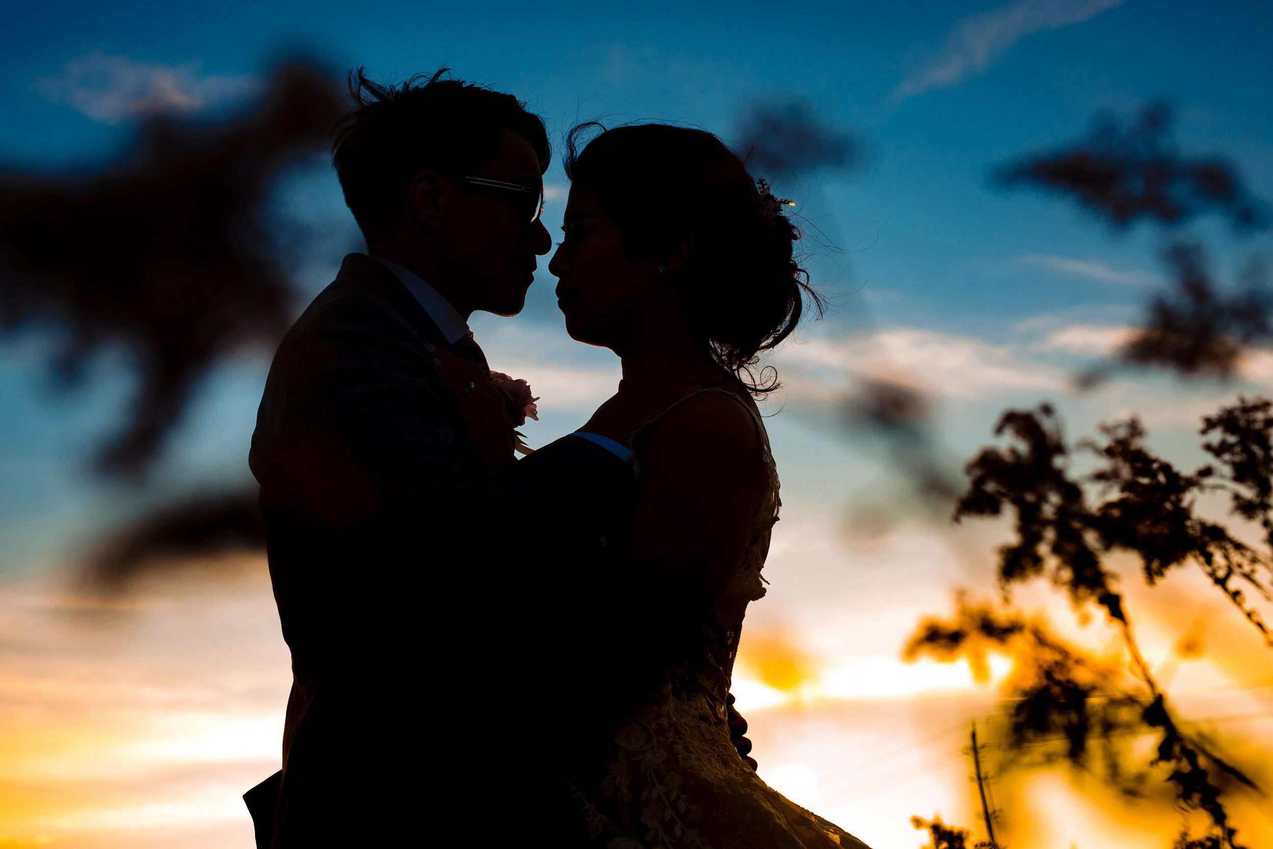 Silhouette of couple in romantic embrace against dramatic sunset sky.