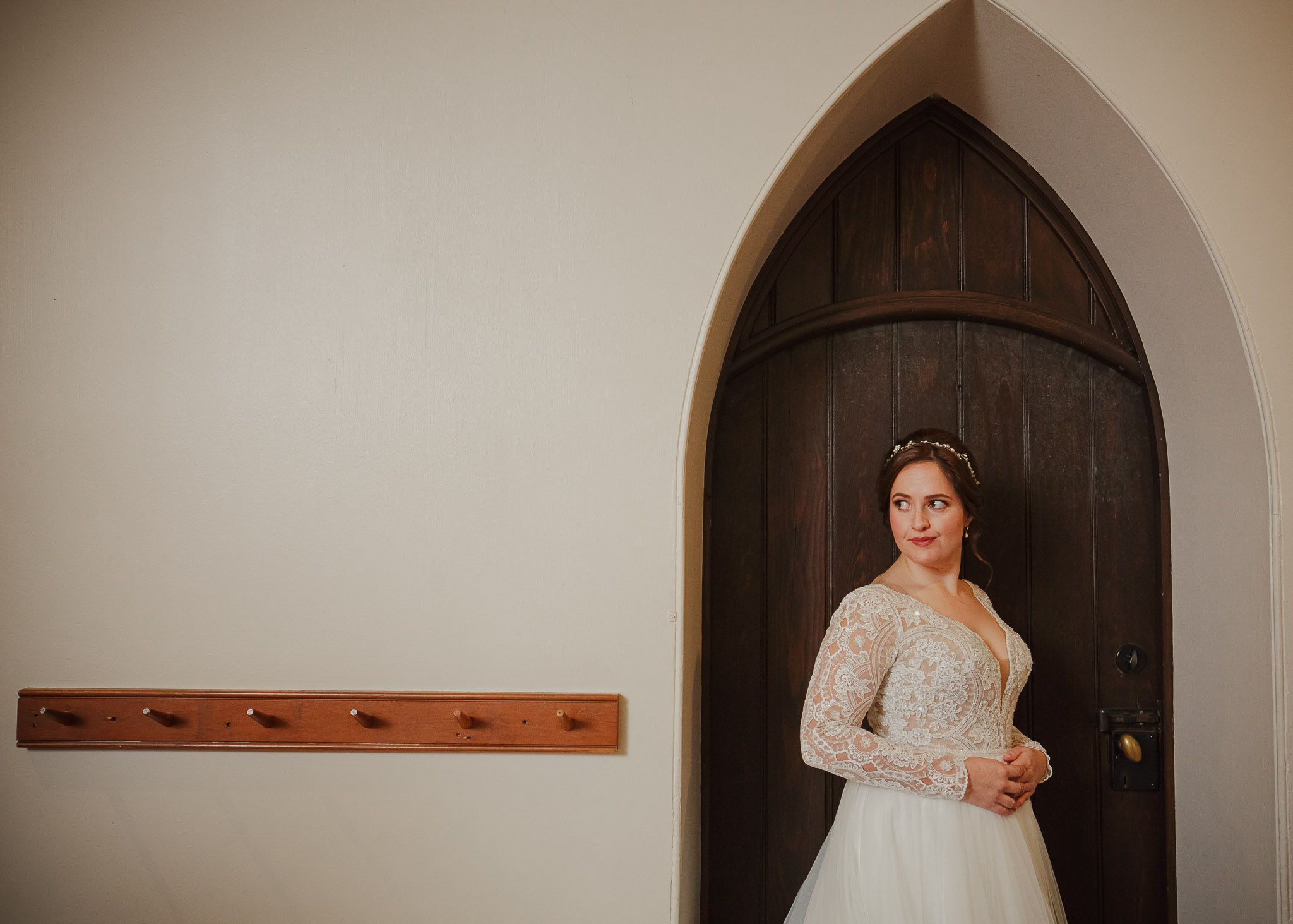 Classic bridal portrait framed by gothic arched wooden doorway in church setting.