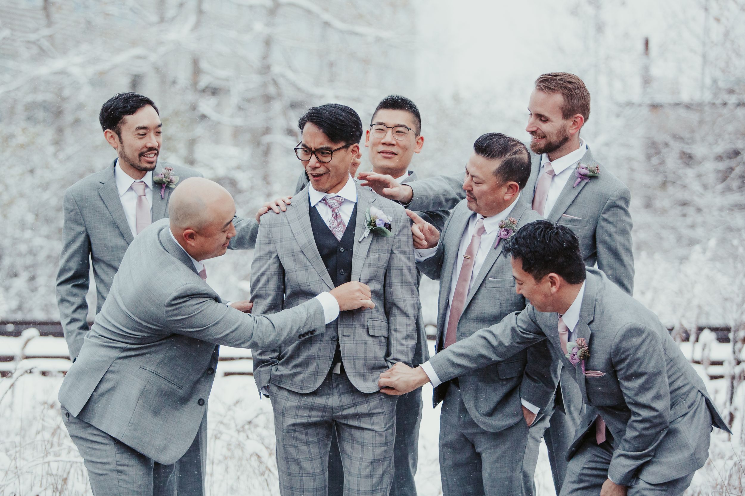 Groomsmen in gray suits sharing a laugh during wedding festivities.