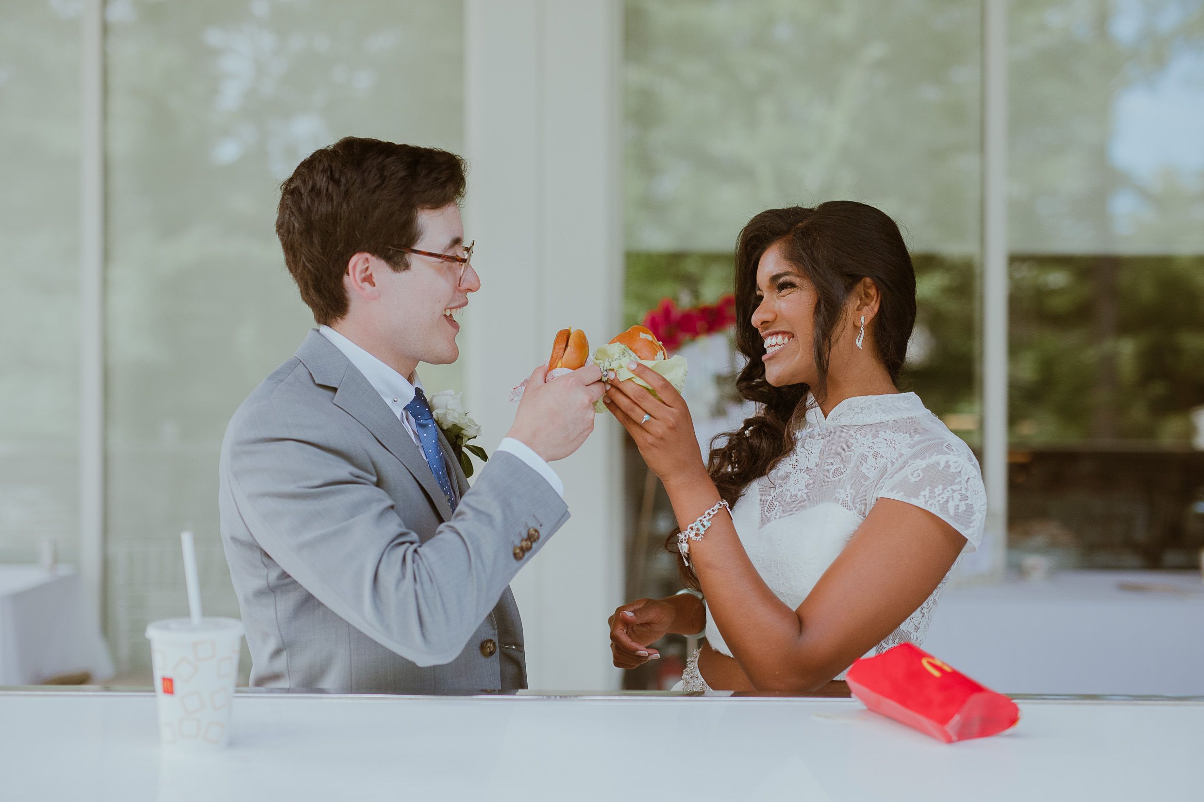 Couple shares drinks and laughs at table during wedding celebration.