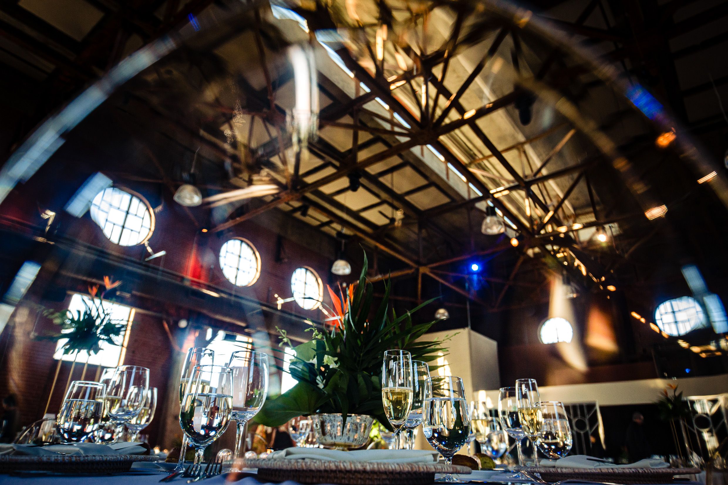 Elegant table settings under dramatic lighting and exposed beams at an upscale restaurant venue.