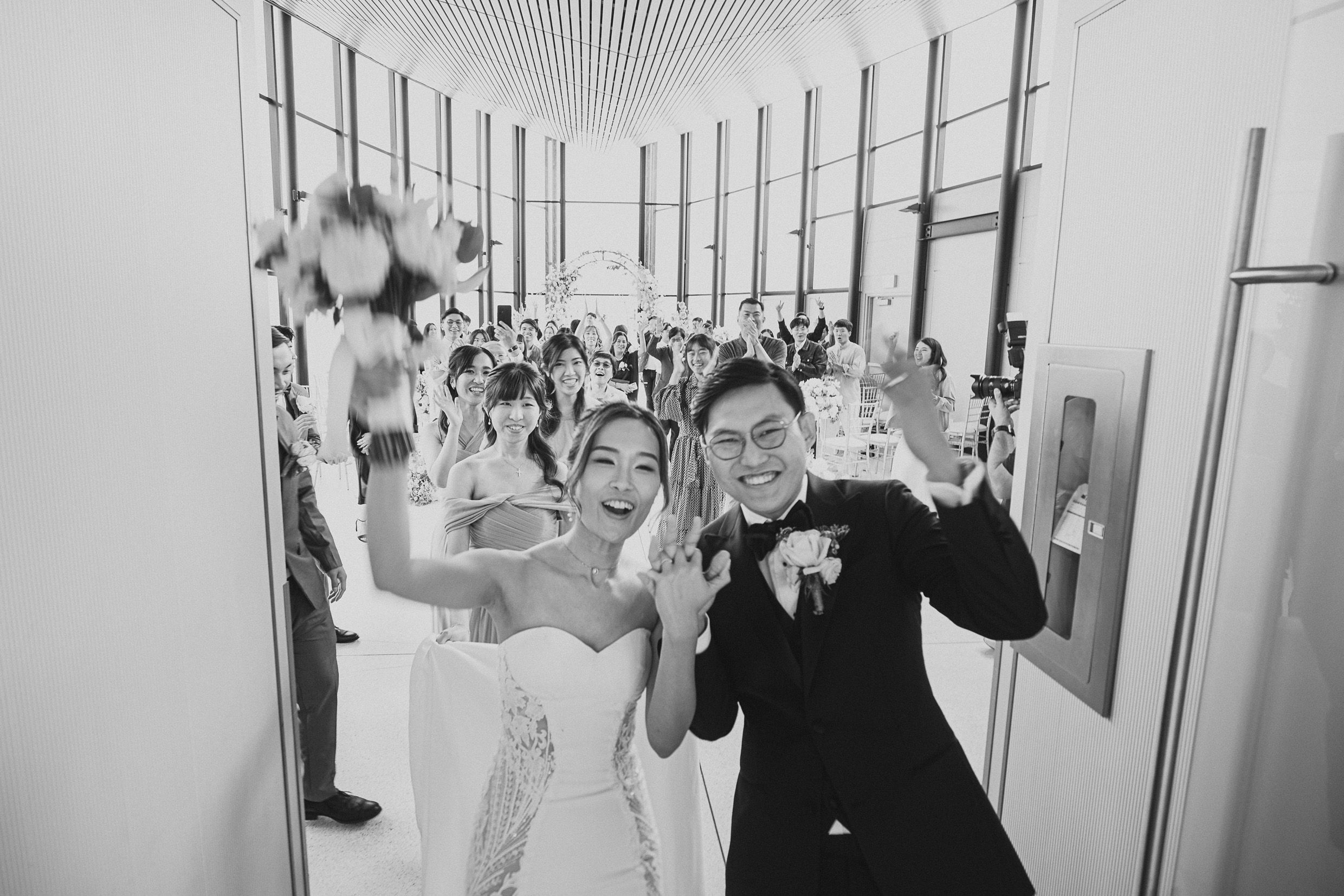 Black and white candid celebration shot in modern hallway with balloons and festive energy.
