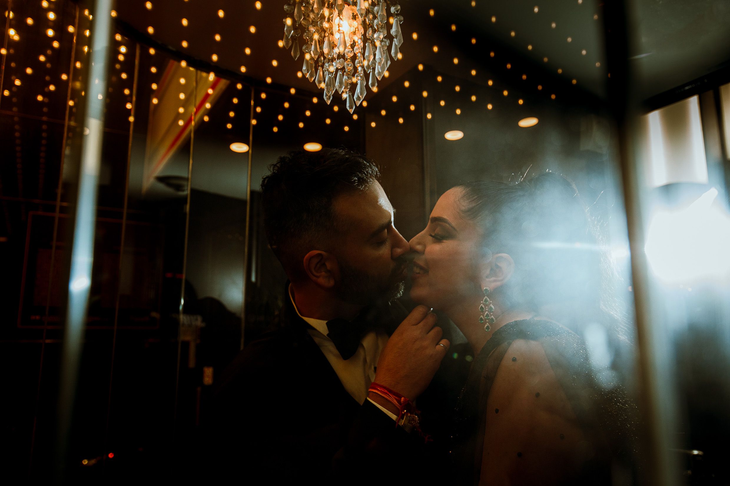 Romantic couple embraces under twinkling lights in intimate setting.
