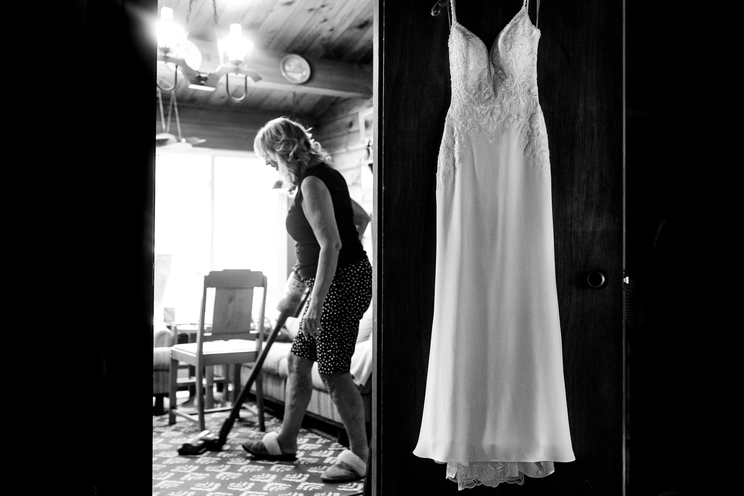 Black and white photo of wedding preparations with a white dress hanging.