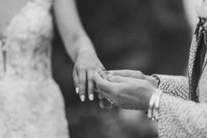 Close-up black and white photo of hands displaying wedding rings.