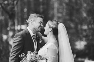 Black and white intimate wedding portrait captured in a forest setting.