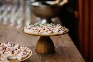 Rustic wooden cake stand displays decorated desserts on wooden table.