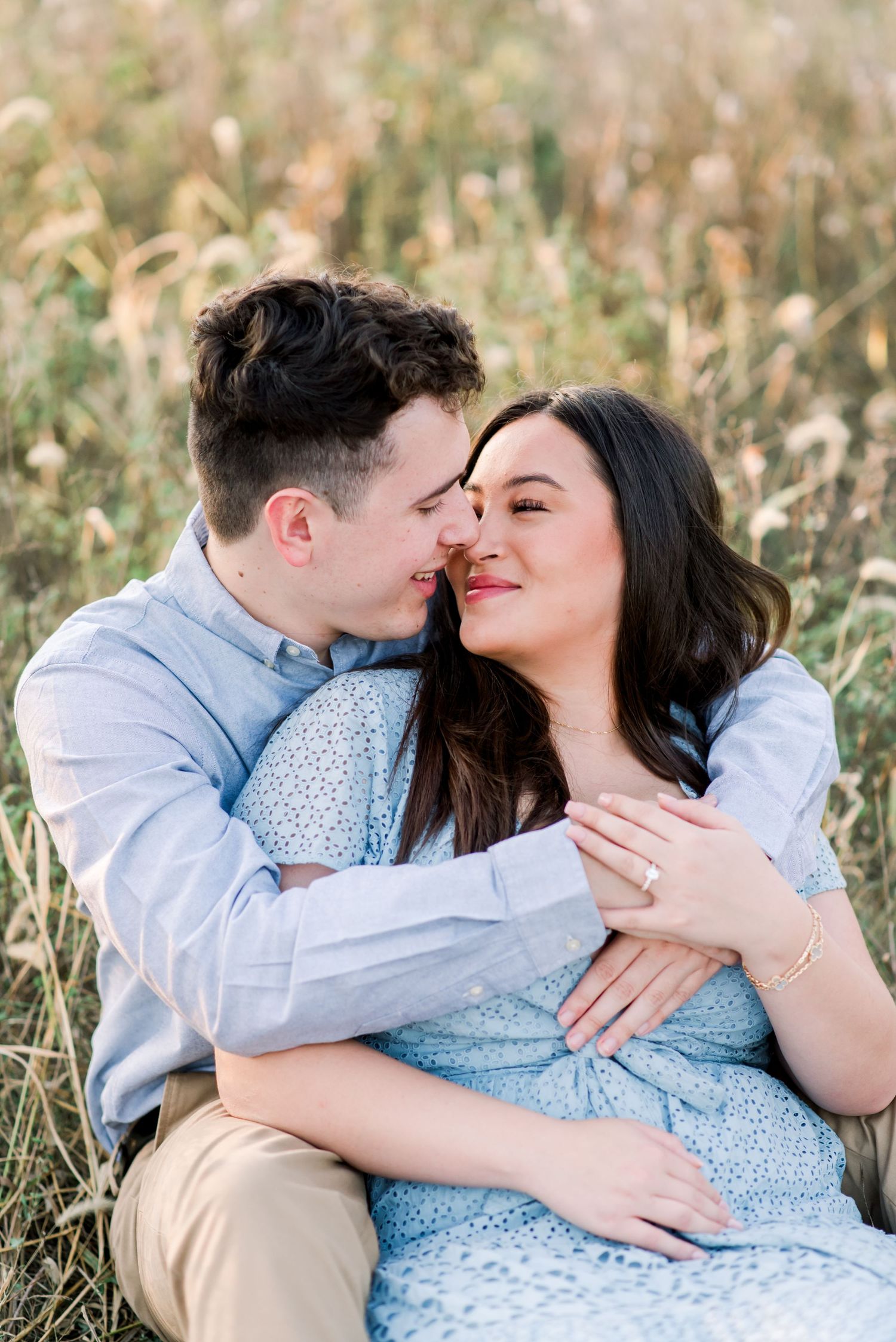 Romantic couple embracing in a golden field during sunset wearing coordinated blue outfits.  Fairfield Lakes Park Lafayette, IN