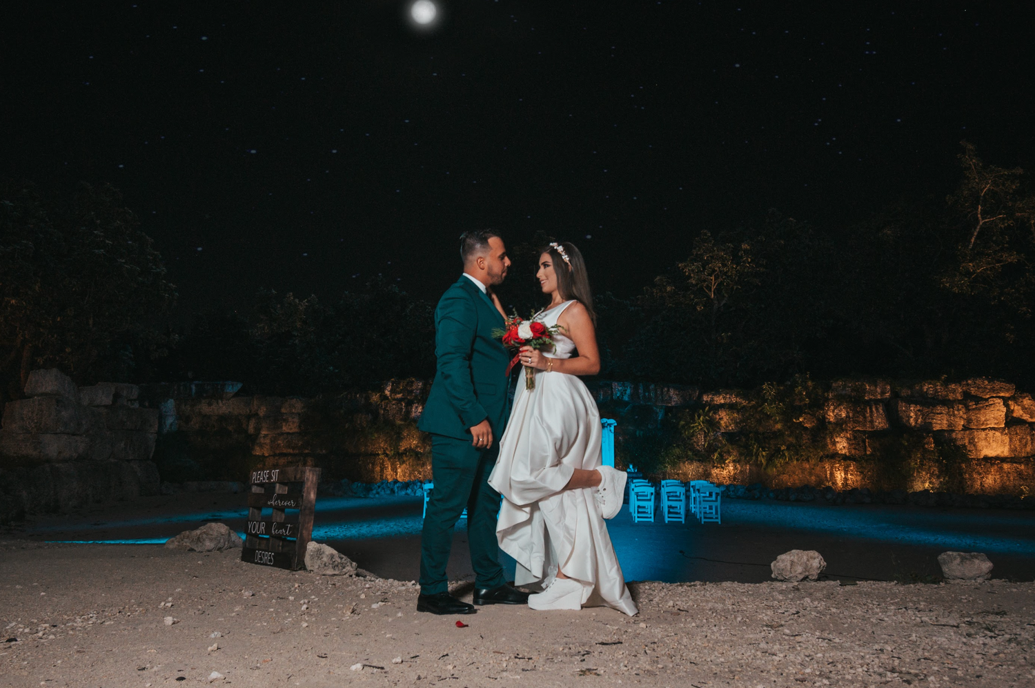 Wedding couple embracing under moonlight in romantic nighttime setting.