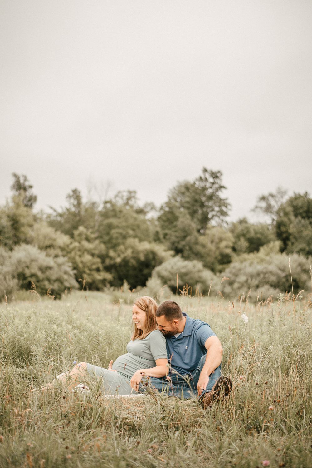 Couple sitting together in golden meadow during sunset.