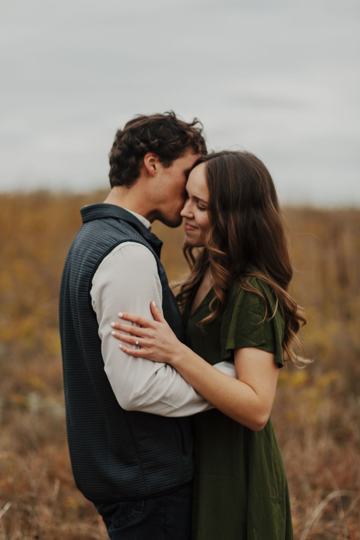A romantic outdoor portrait of a couple embracing on a warm autumn day in a field.