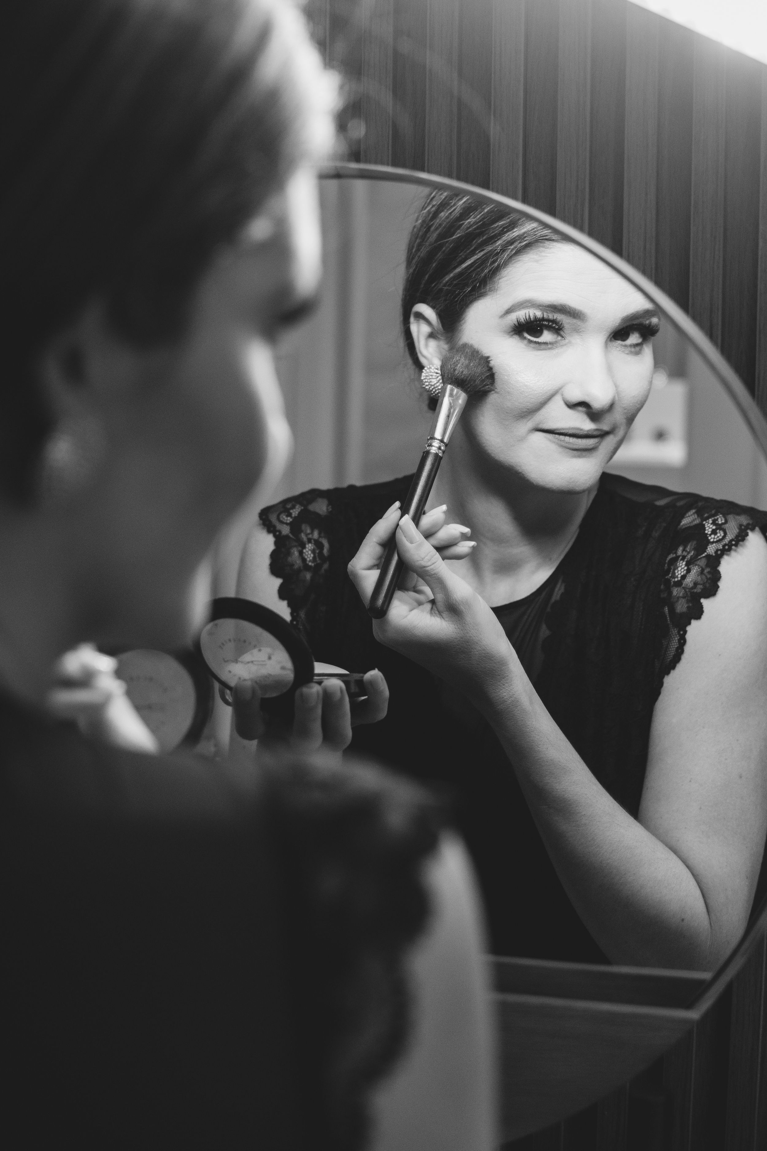 Black and white series showing someone applying makeup in a mirror with artistic composition.