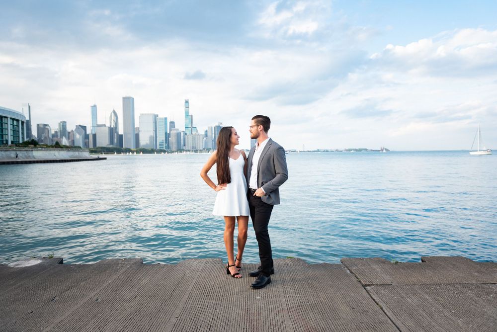 A recently engaged couple standingon the shore of Lake Michigan with the Chicago skyline in the background.