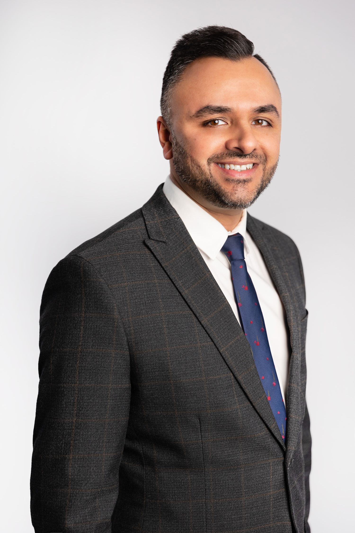 Smiling man in gray suit and blue tie posing for professional headshot.