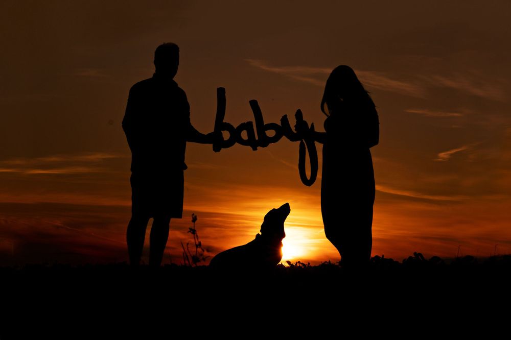 Silhouettes of people against dramatic orange sunset sky.