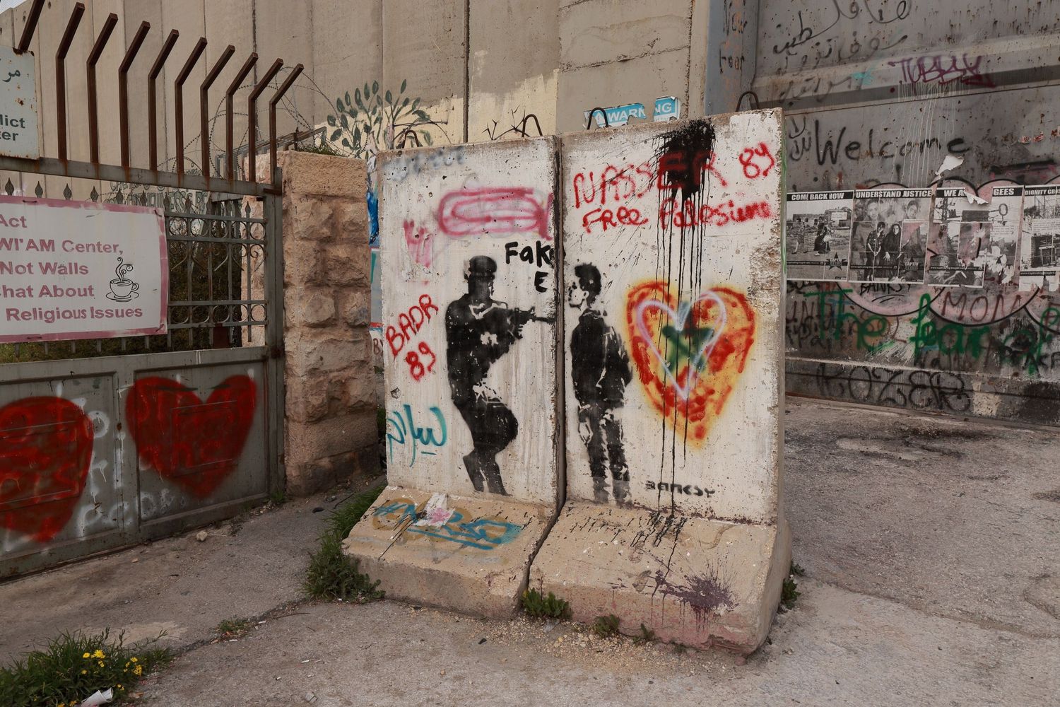 Street art on a concrete wall depicts silhouettes and heart symbols with graffiti in an urban setting.