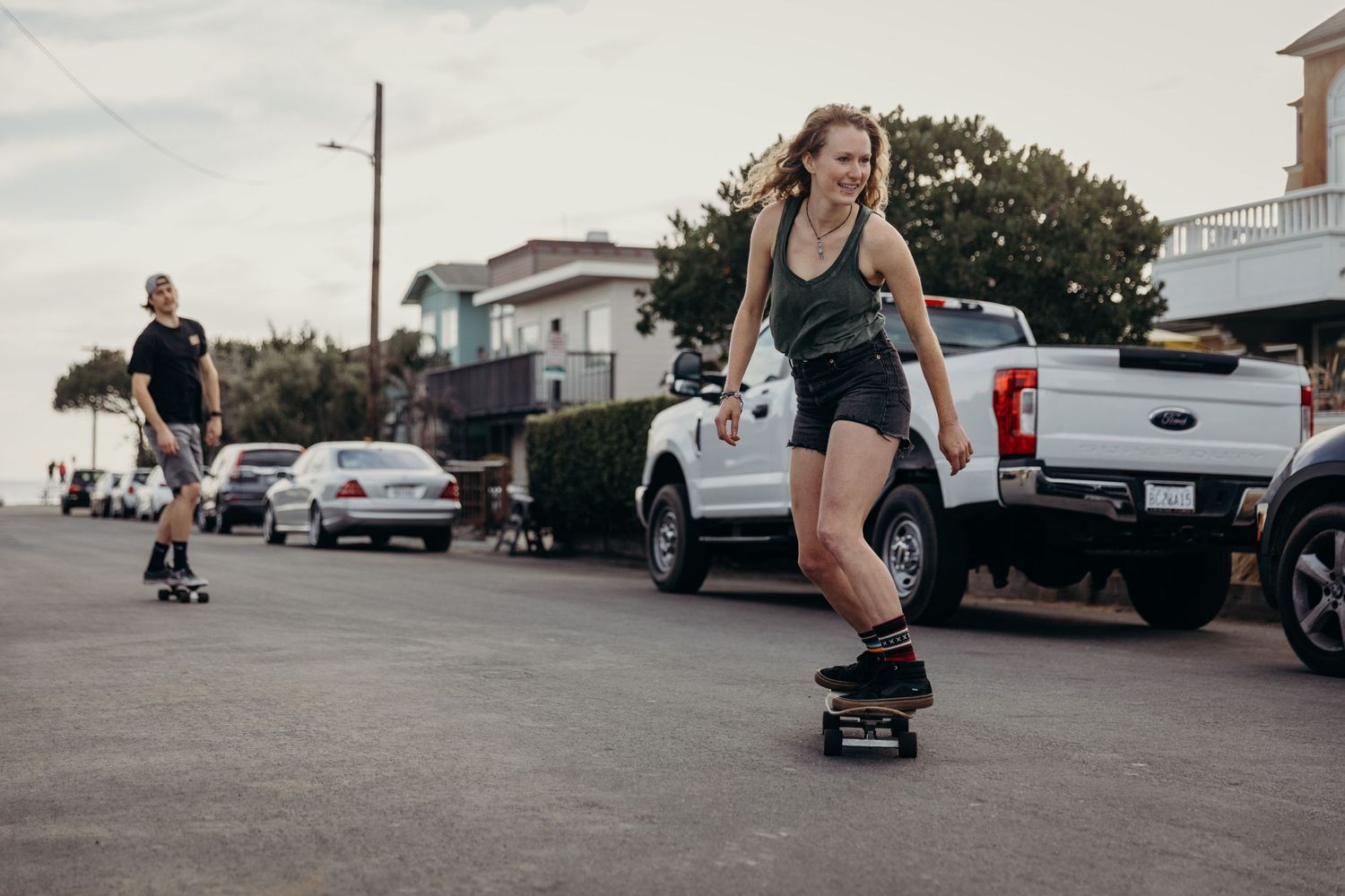 A skateboarding session on an urban street with parked cars in the background.