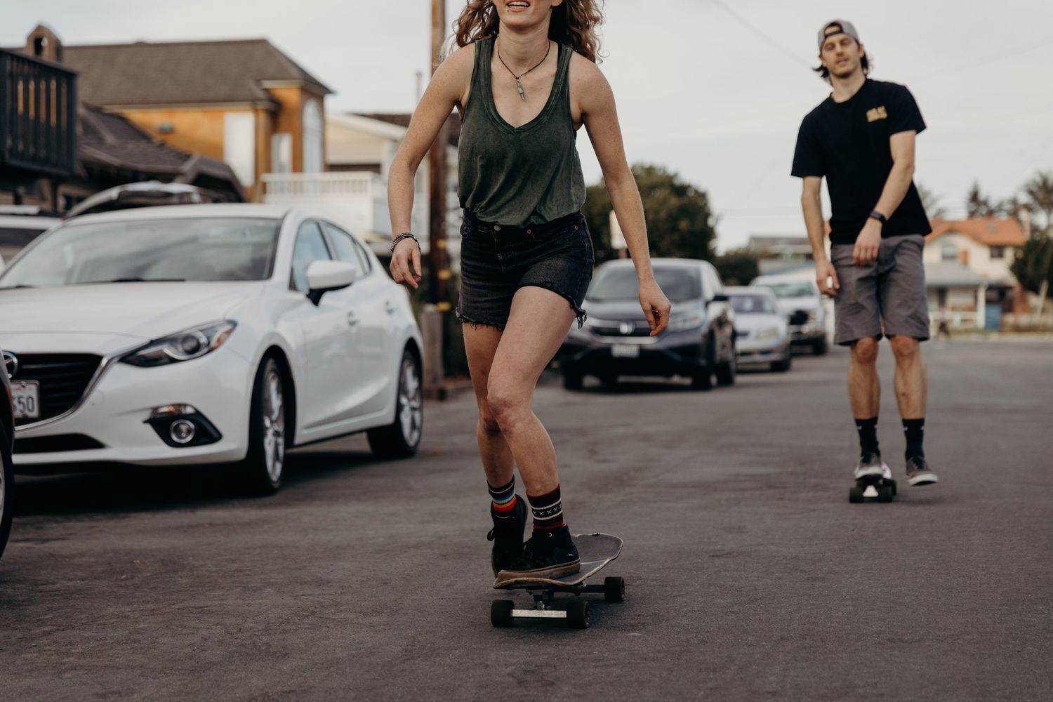 Skateboarding on an urban street with white cars parked along the curb.