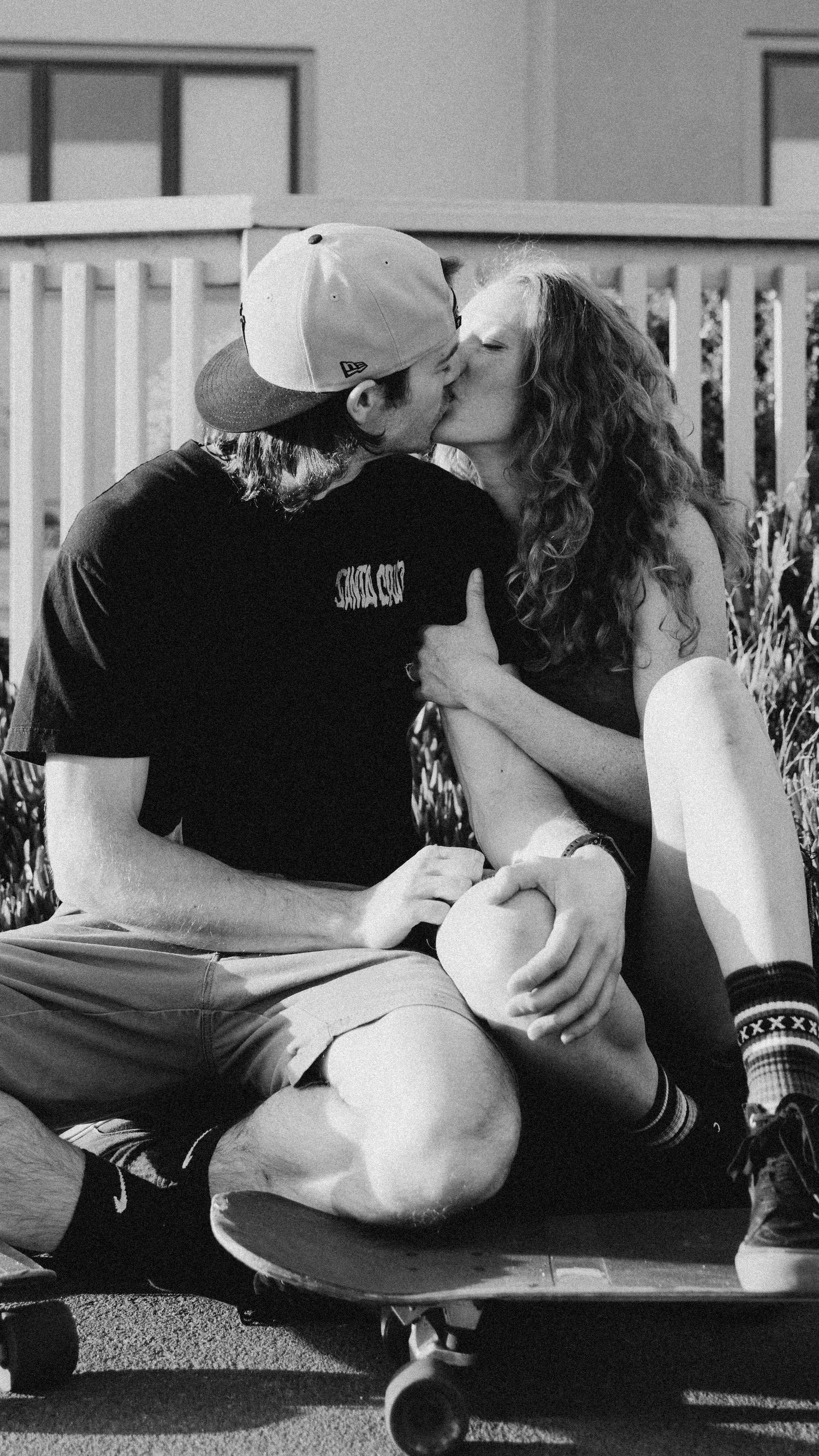 Black and white intimate moment shared between couple on skateboard deck.