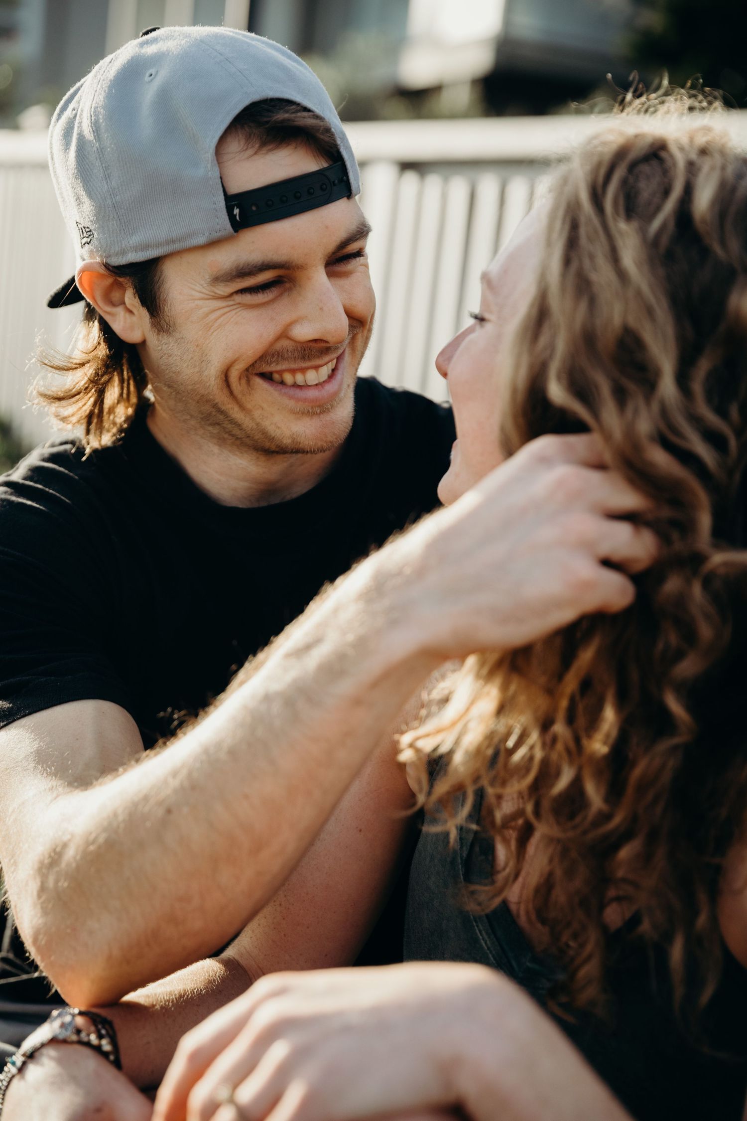 A tender outdoor moment shared between a couple against a white fence backdrop.