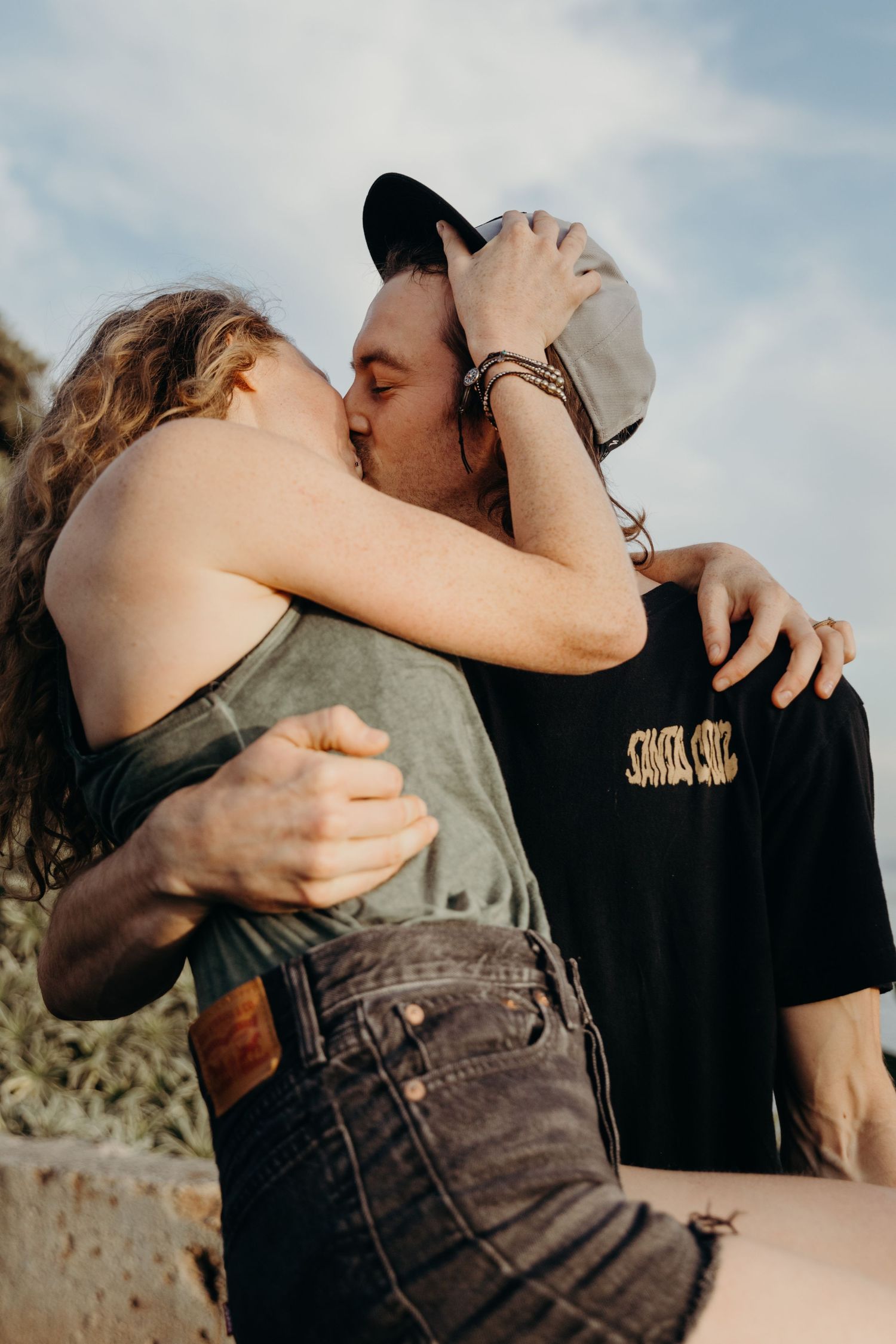Romantic couple sharing an intimate moment against blue sky and palm trees.