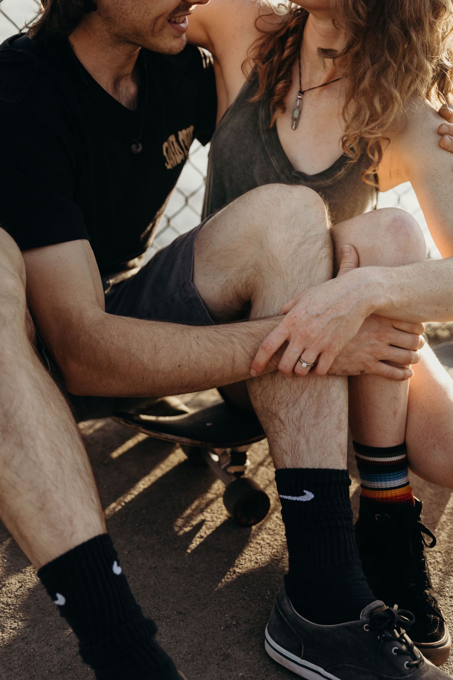 Intimate moment between couple in athletic wear sitting by fence.