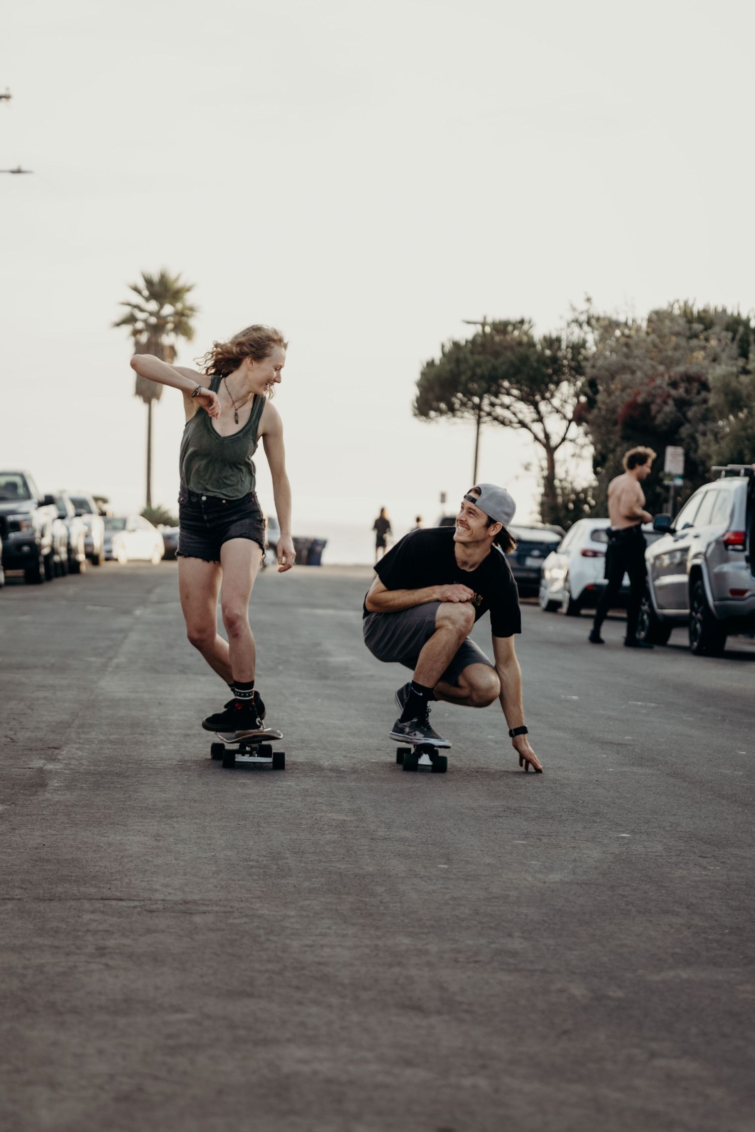 Two people skateboarding together on an urban street at sunset.