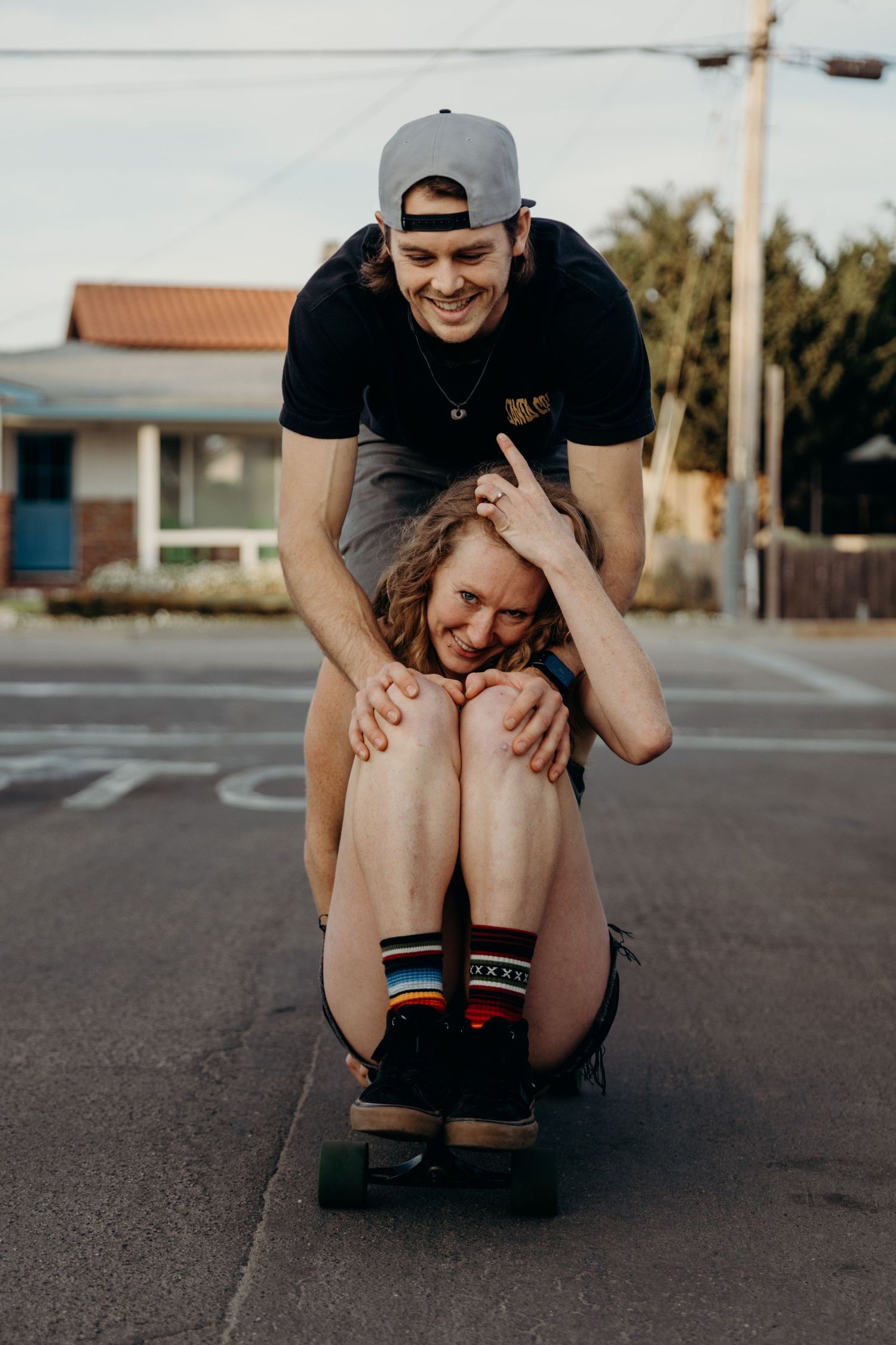 Playful skateboarding moment between couple on empty street.
