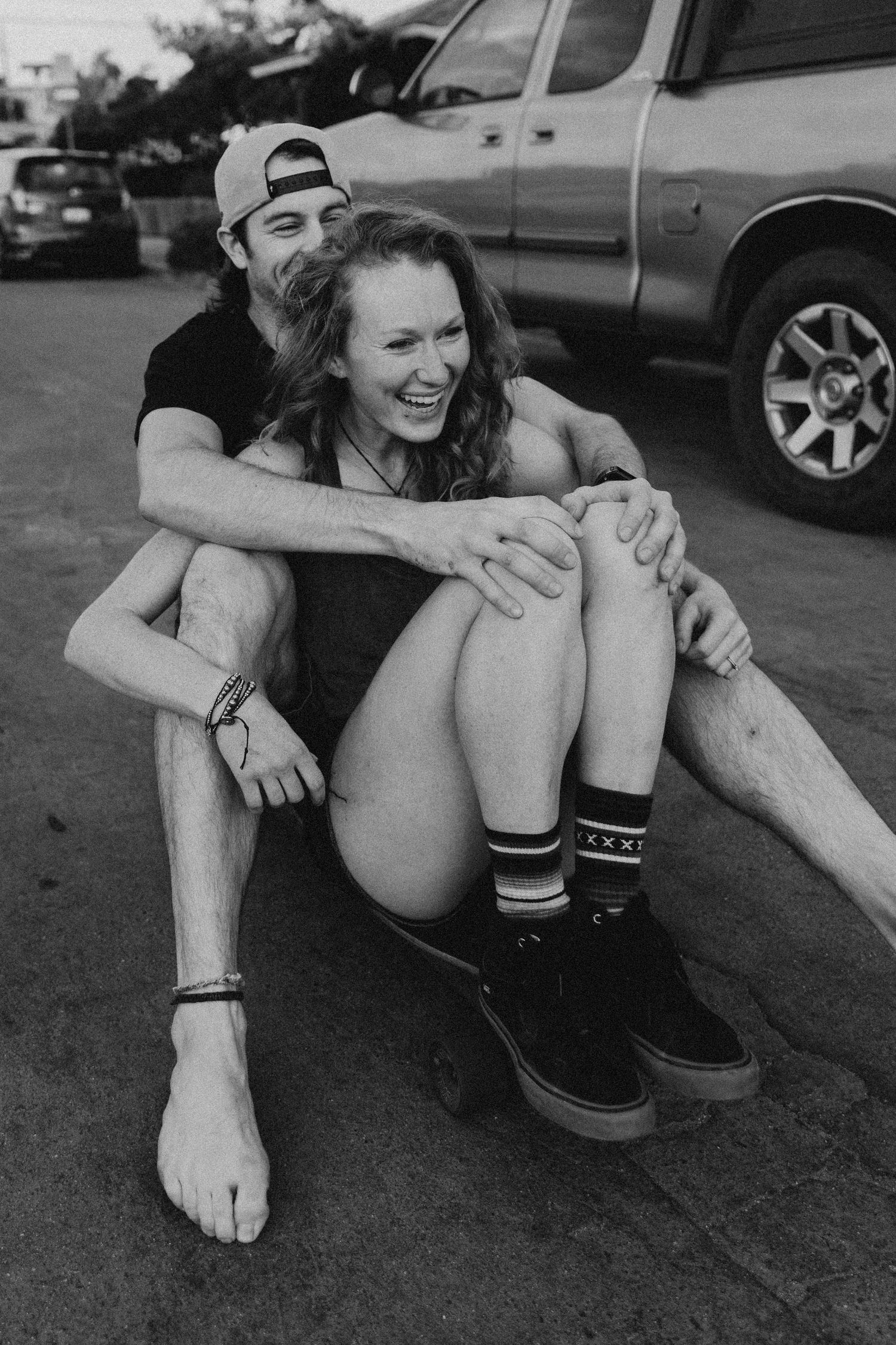 Black and white portrait of couple laughing together on pavement.