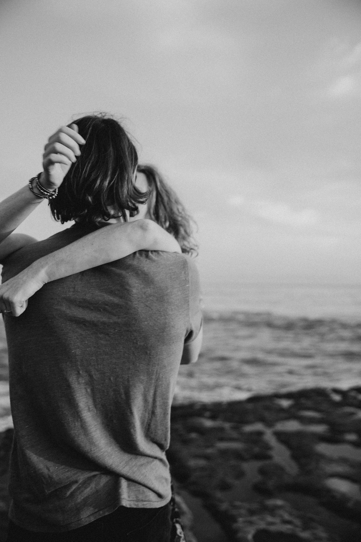 Silhouette of embrace against ocean backdrop in black and white.