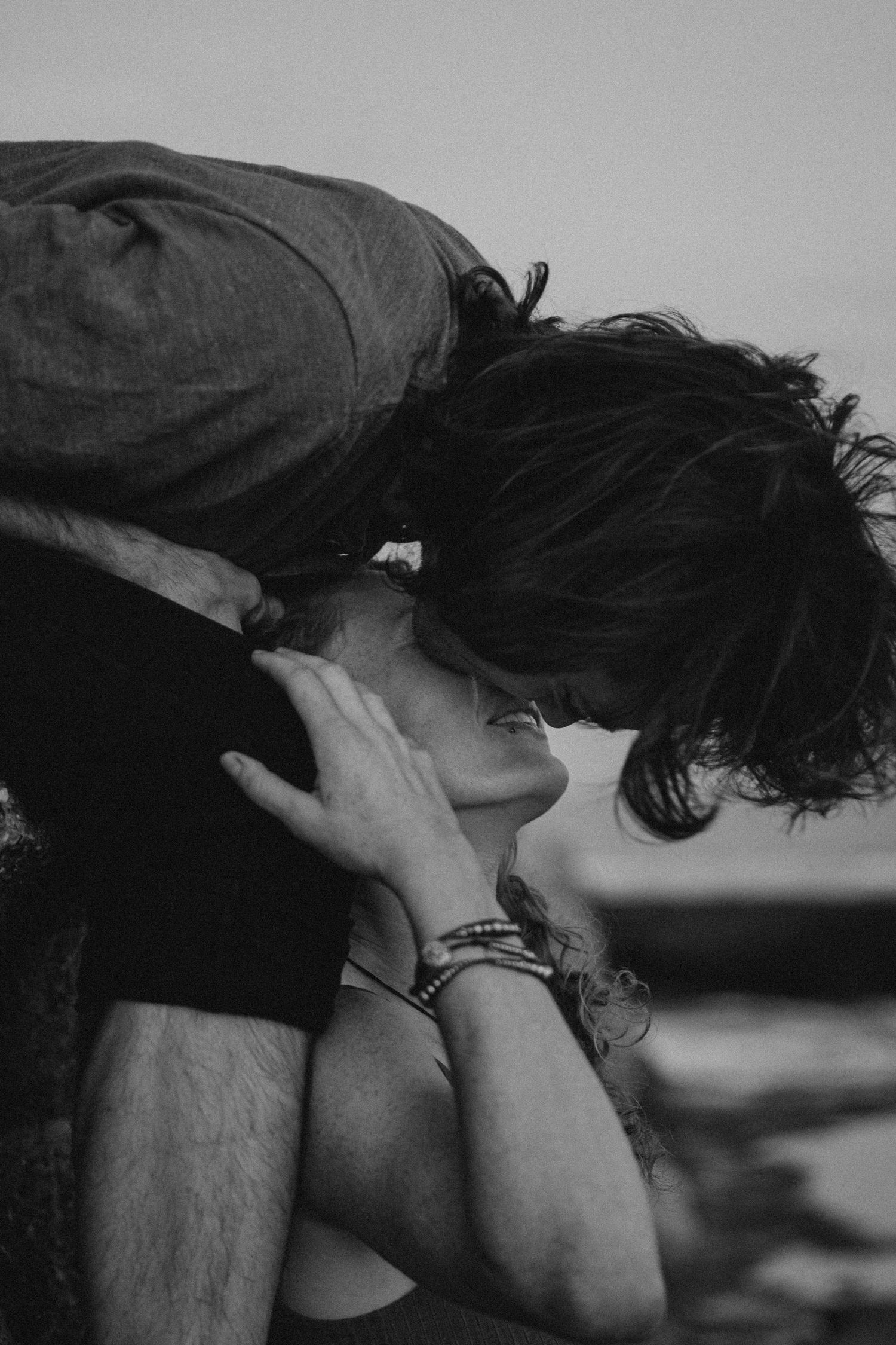 Intimate black and white portrait of couple sharing passionate moment outdoors.