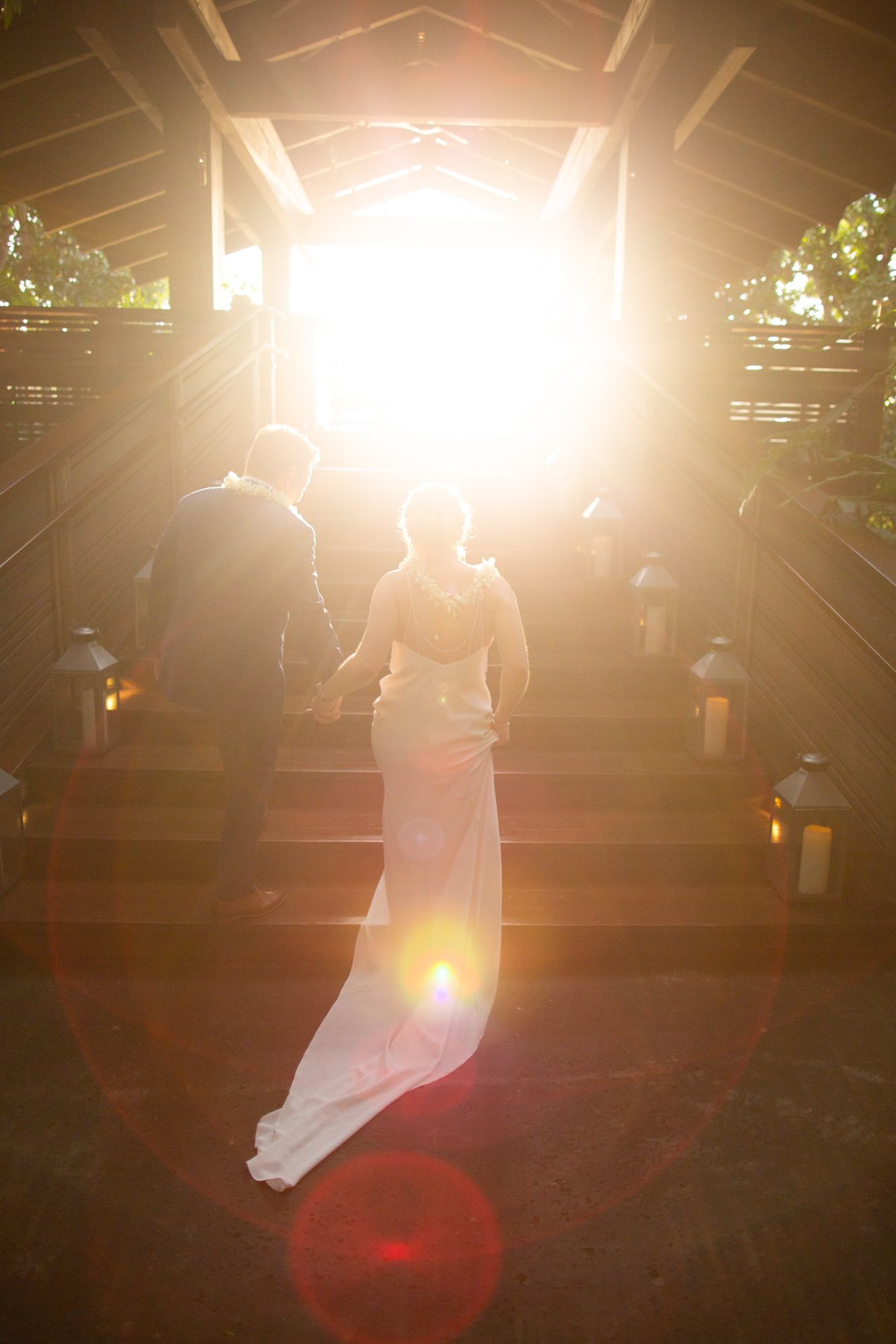 Light shines through a covered walkway as a couple walks through during their wedding ceremony.