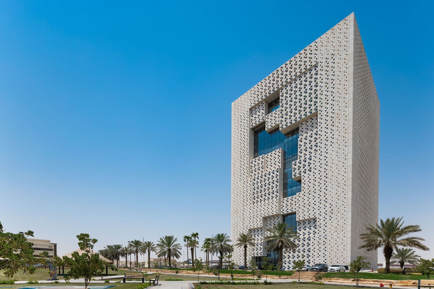 Contemporary white architectural structure with geometric patterns and blue sky backdrop.