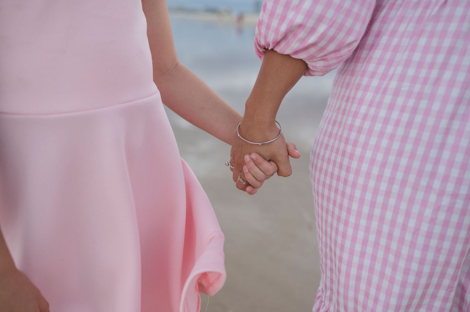 Close-up of hands holding while wearing pink and gingham outfits.