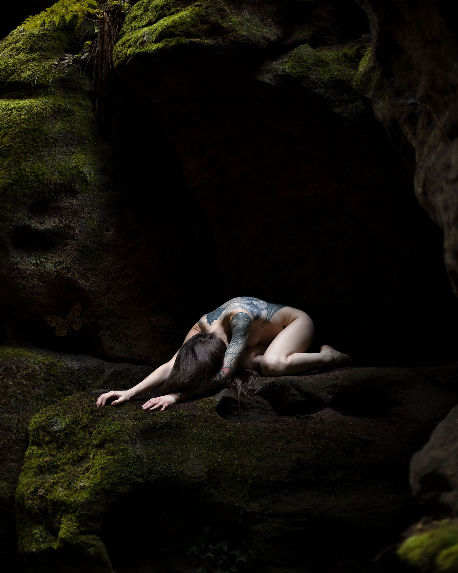 woman with tattoos emerging from dark cave