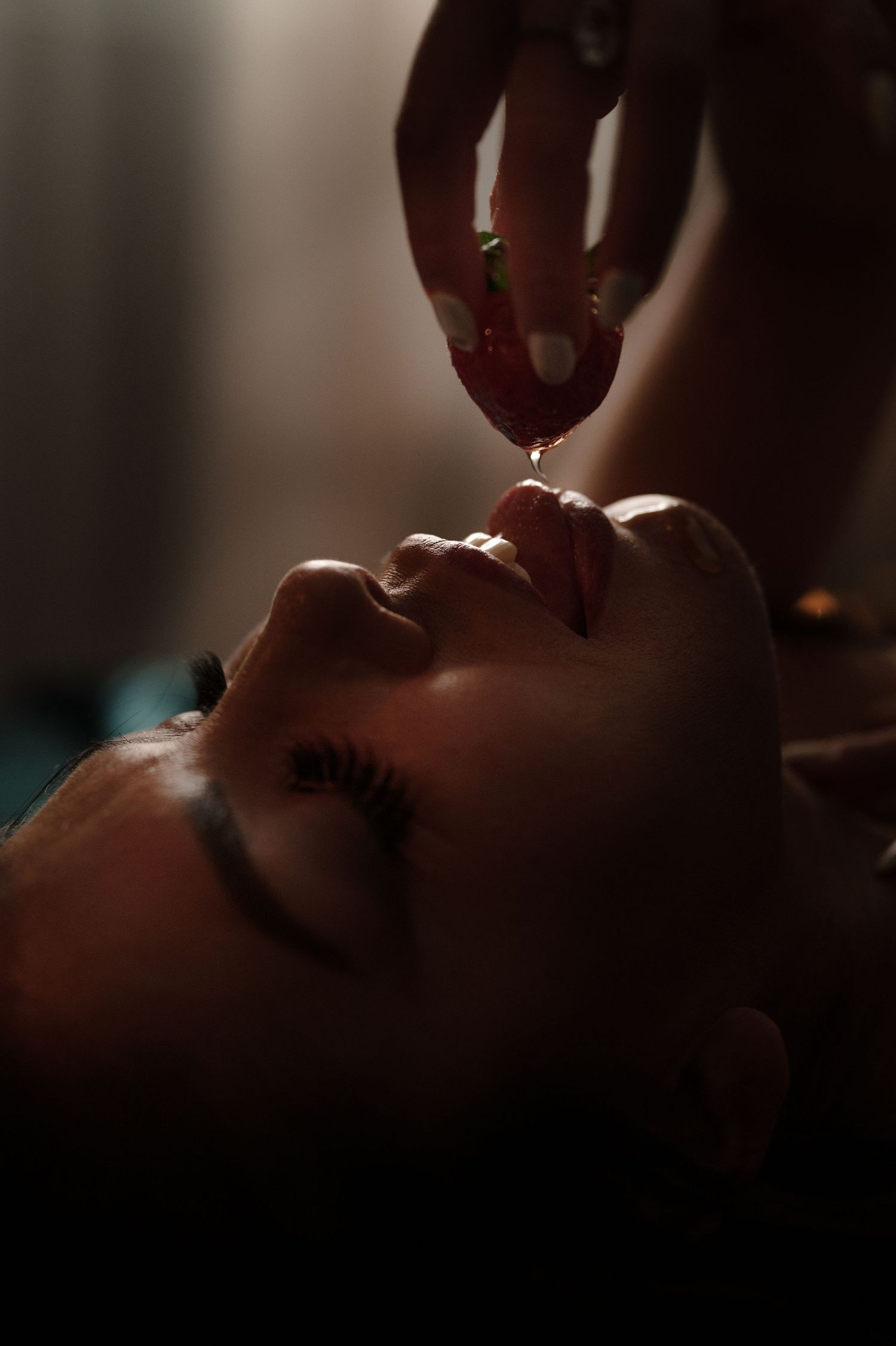 Dramatic close-up shot with moody lighting and red-painted fingernails.