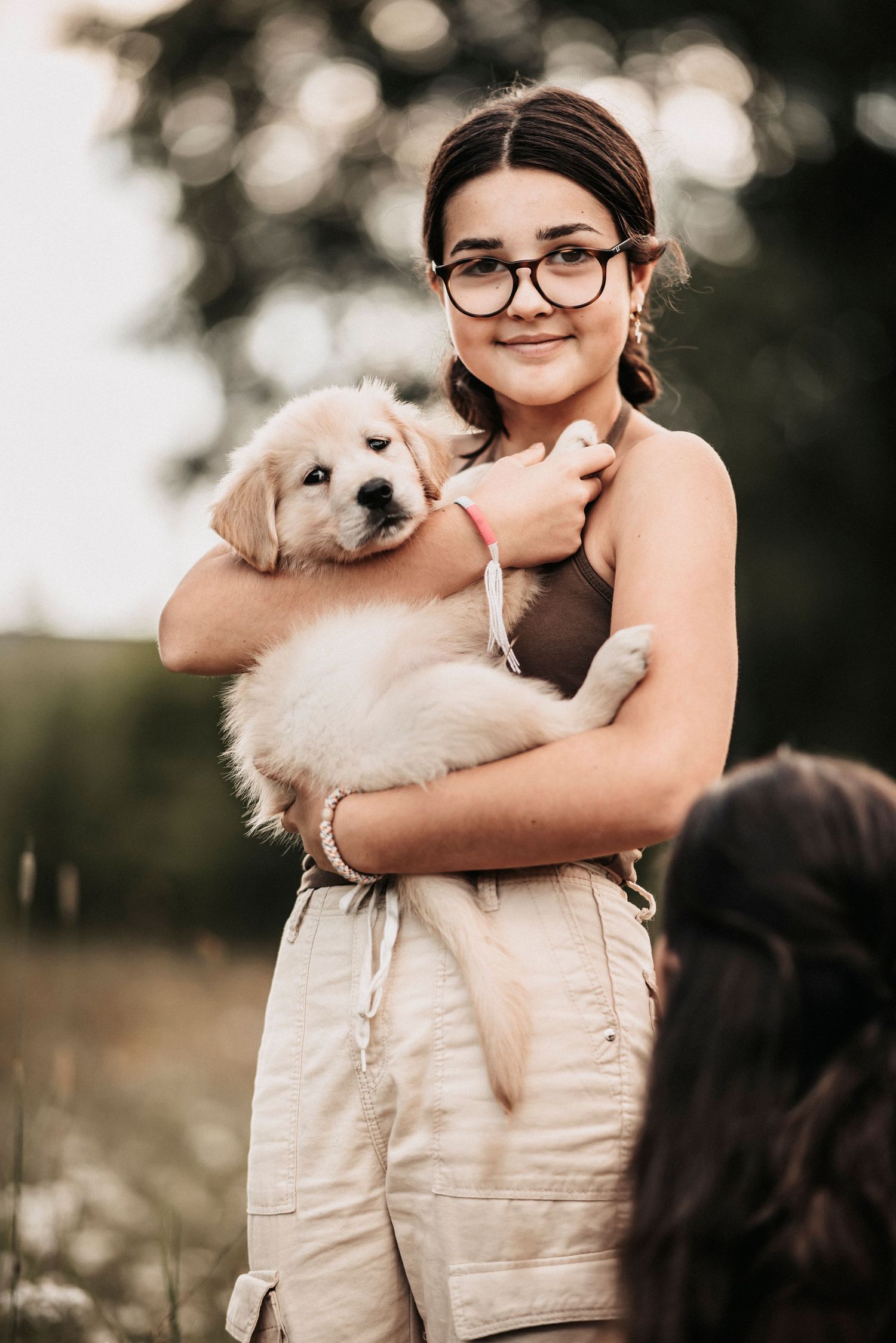A white puppy is cuddled close in a tender embrace outdoors in natural lighting.