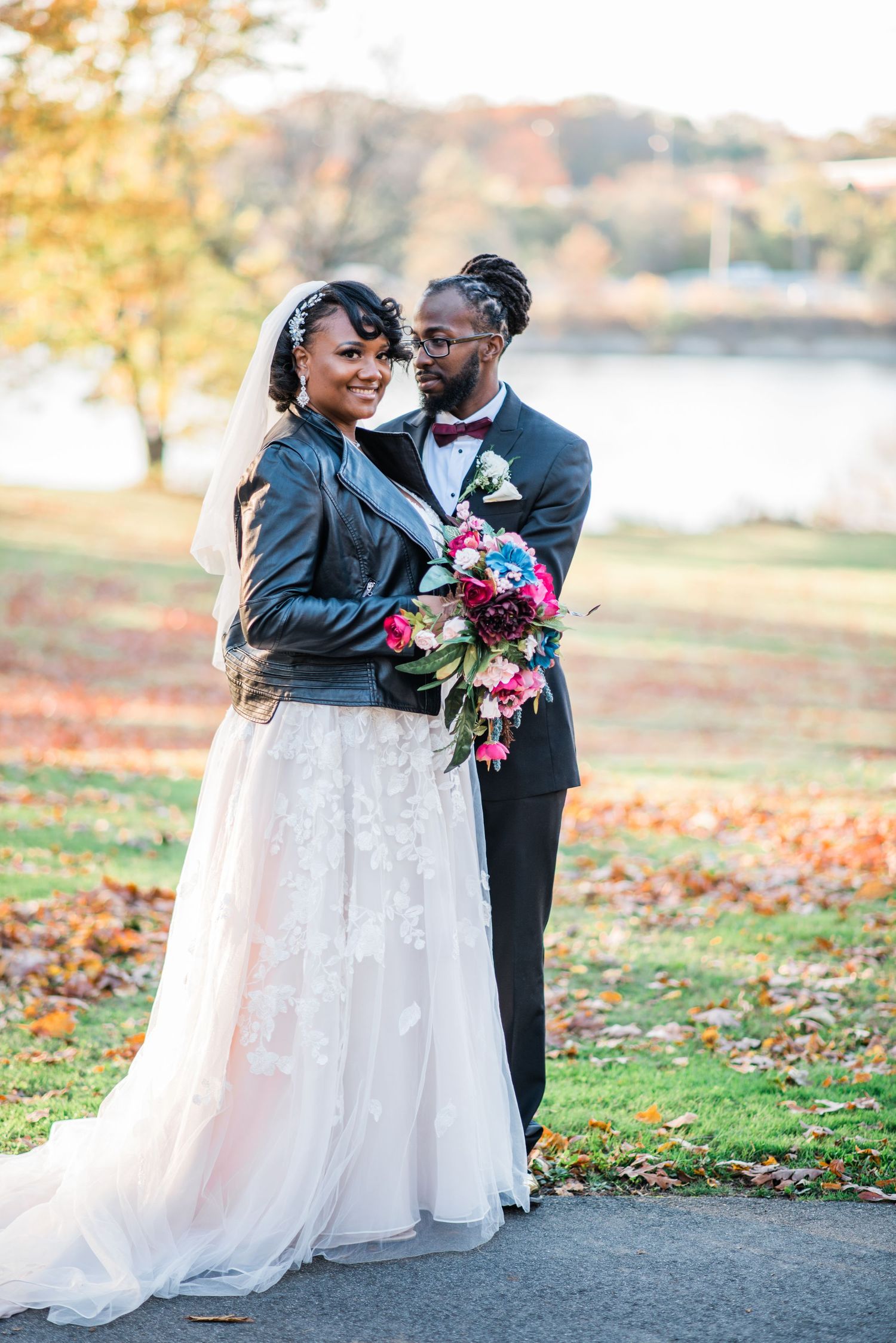 An autumn wedding portrait with colorful bouquet and leather jacket accent.