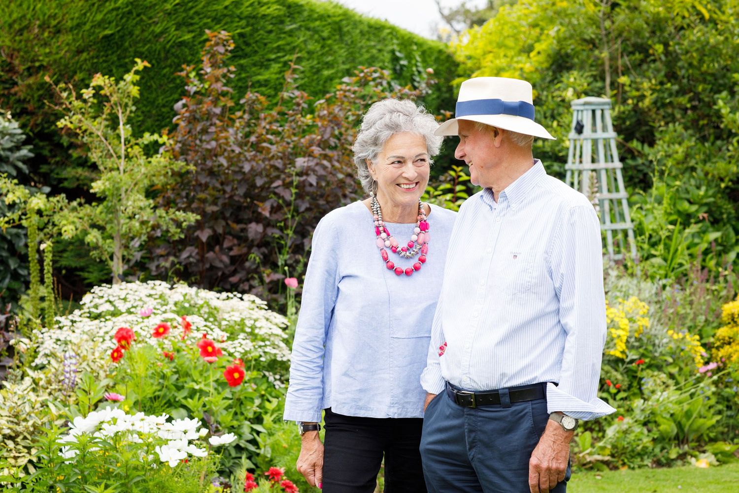 Senior couple enjoying a colorful garden filled with blooming flowers in summertime.