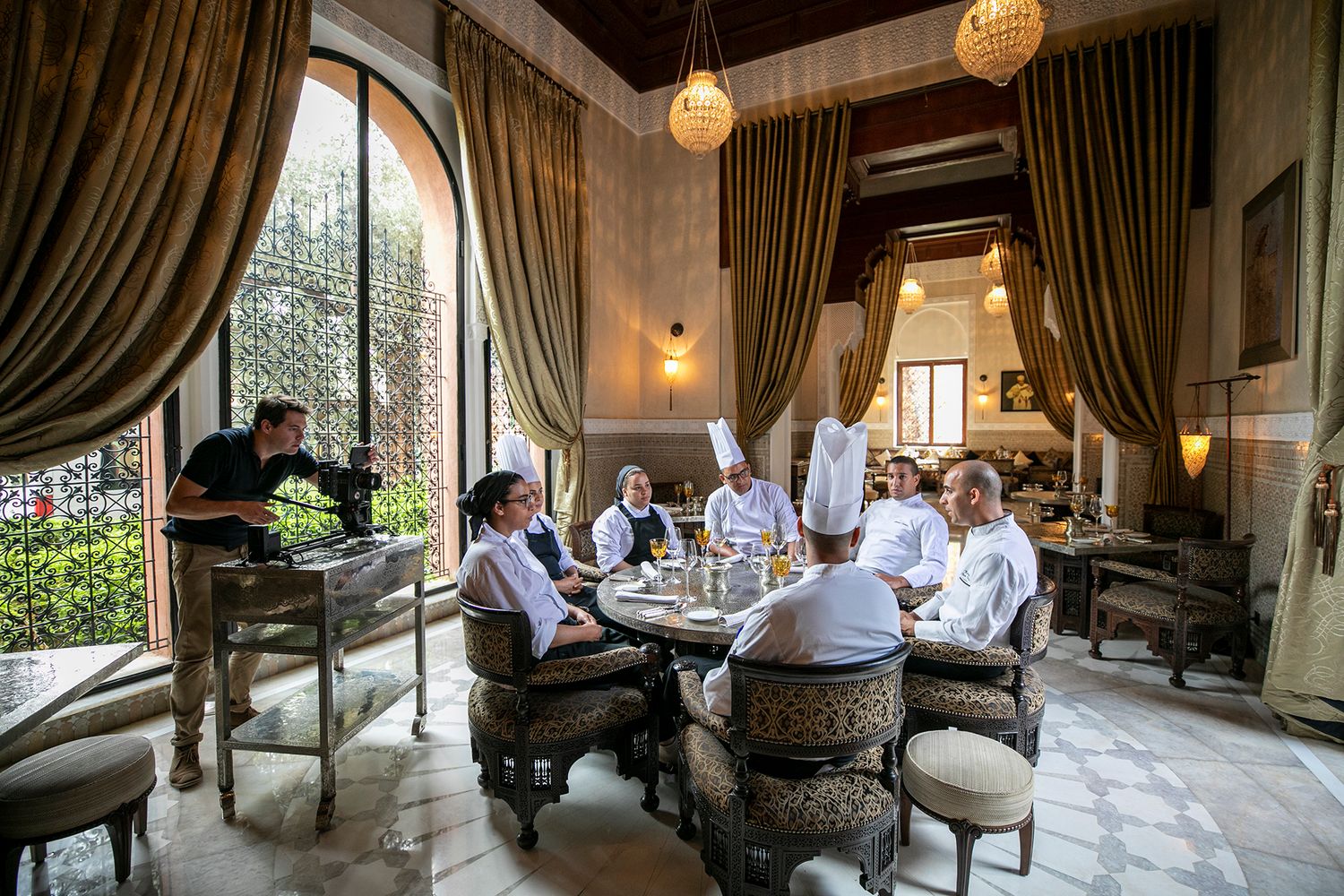 Group dining at an elegant restaurant with arched windows and ornate decor.