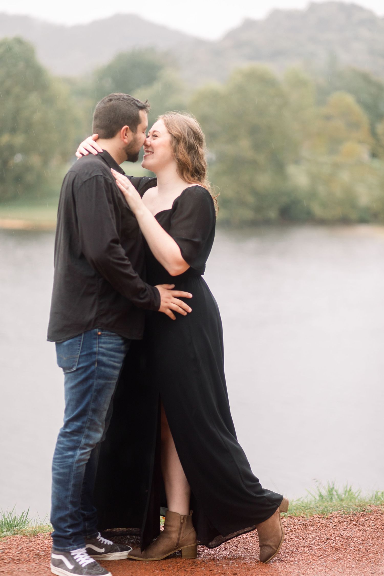Couple sitting together on red ground near peaceful lake during overcast day.