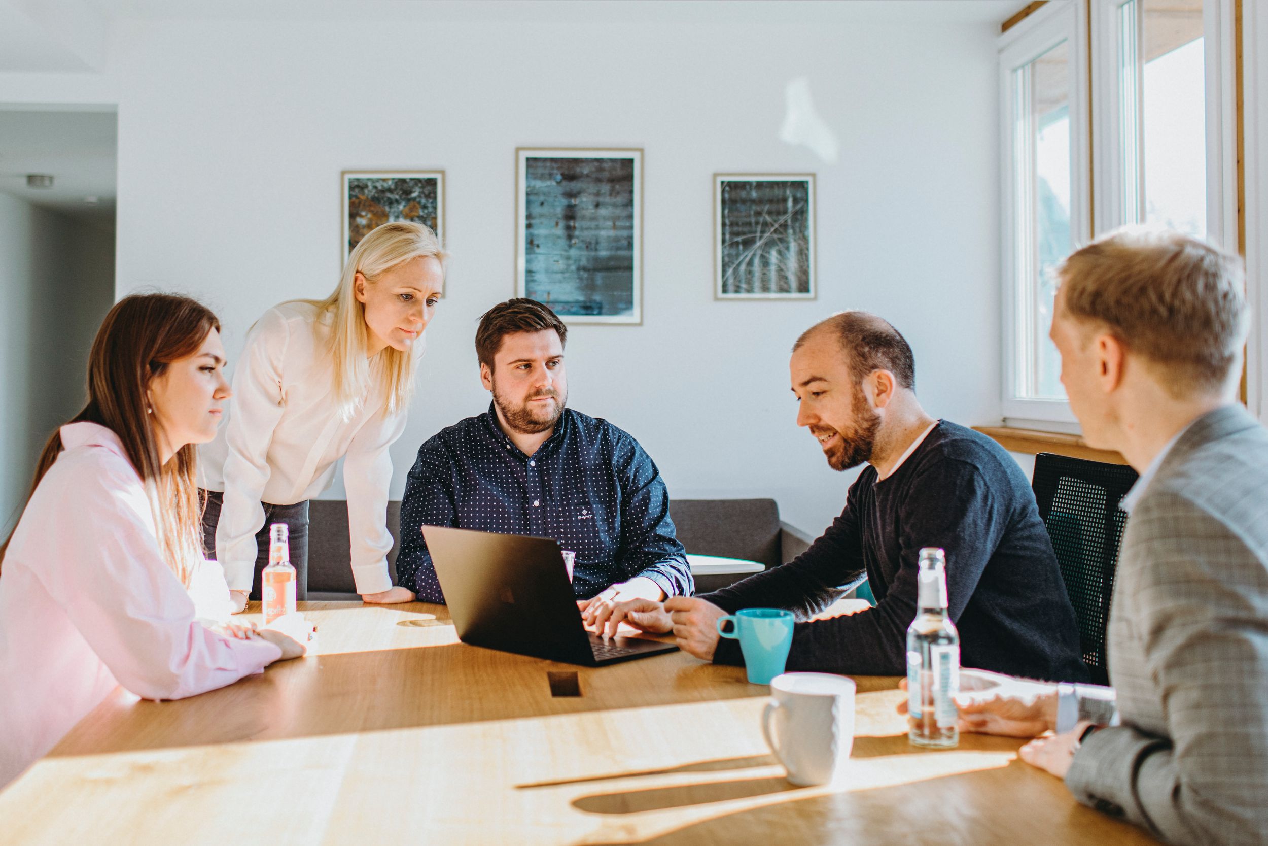 Team meeting in modern office space with people gathered around conference table.