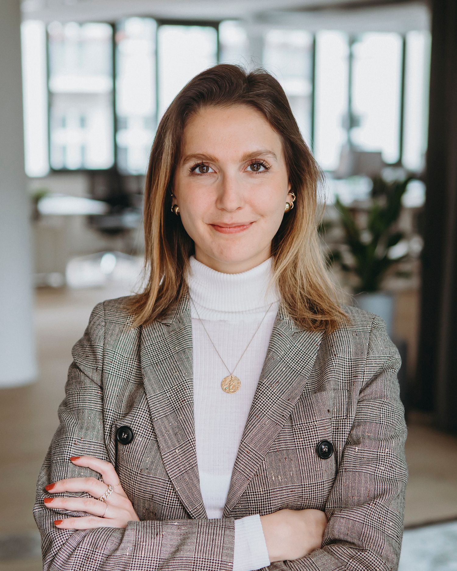 Professional portrait series in grey blazer and white turtleneck against office background.