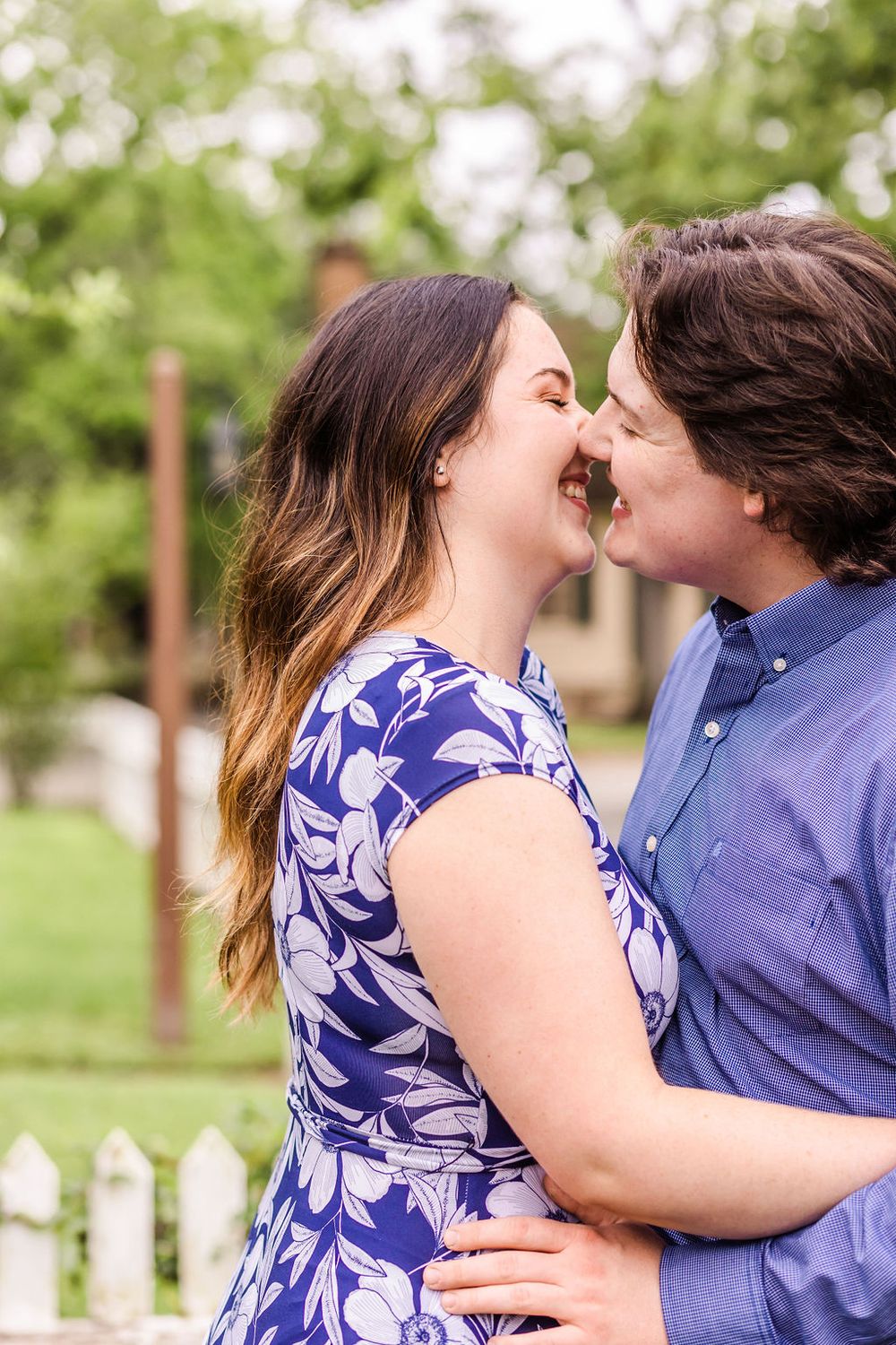 Couple shares joyful laugh during intimate moment in garden setting.