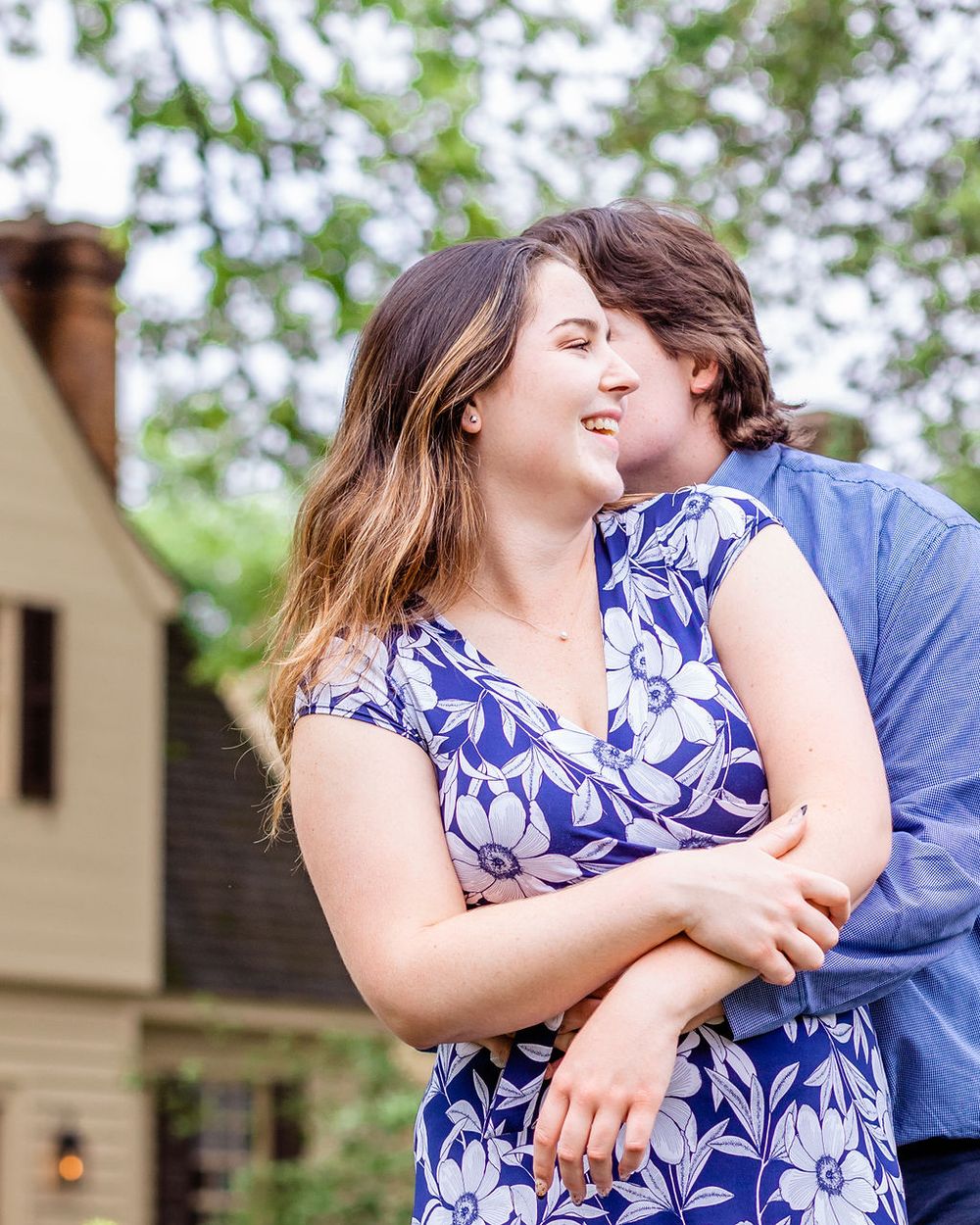 Intimate embrace shared between couple wearing blue against garden backdrop.