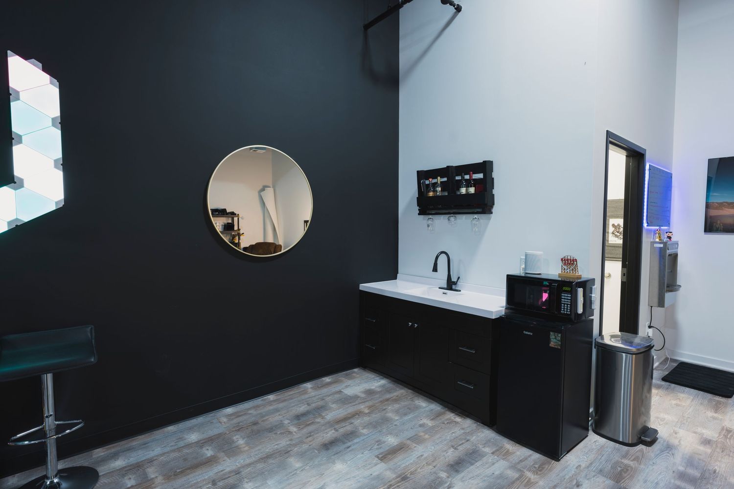Studio room with black walls featuring a circular mirror and small kitchenette area.