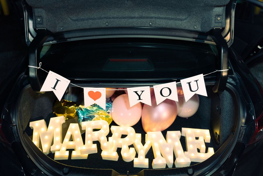 A car trunk decorated with 'I LOVE YOU' banner and illuminated letters for a romantic proposal.