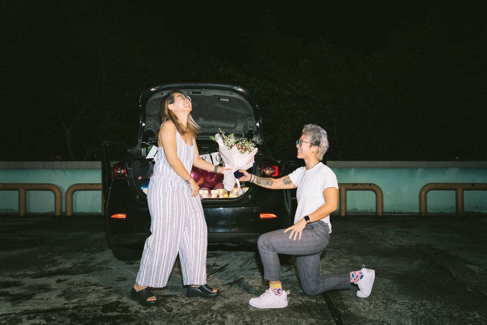 A heartfelt proposal moment captured at night with decorative lights in the background.
